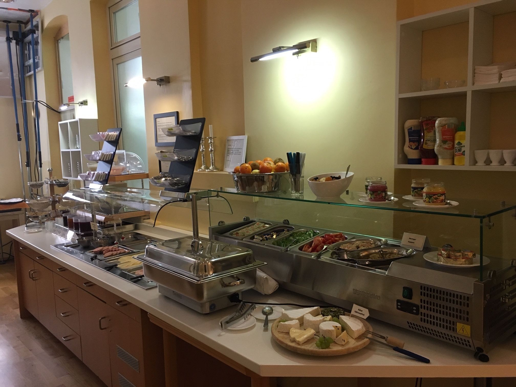 A buffet with various food items, including fruits, cheeses, and meats, displayed in glass containers.