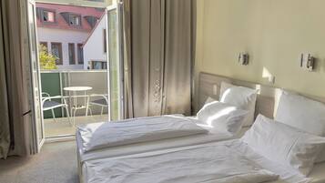 A hotel room with a bed, a small table, and chairs outside the window.