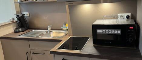 A modern kitchen with a built-in microwave, a kettle, and a coffee maker.