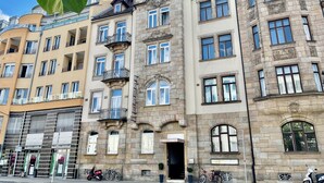 Un hotel de varios pisos con entrada central, balcones y fachada de piedra.