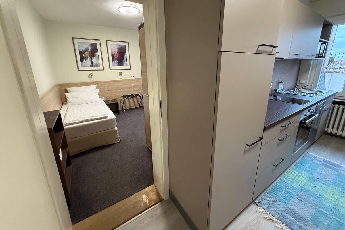 Habitación de hotel con cama, un pequeño espacio para sentarse, kitchenette y vistas al exterior.