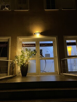 A building entrance with two doors labeled "Cästehaus" and "Matthias". There is a potted plant in front of the entrance, and a small light fixture above the doors. - Gästehaus Matthias (Dresden)