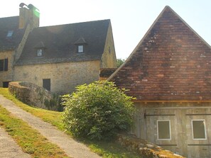 A stone building with a sloped roof and a brick structure with a triangular roof. - Maison Linol (Beynac-et-Cazenac)