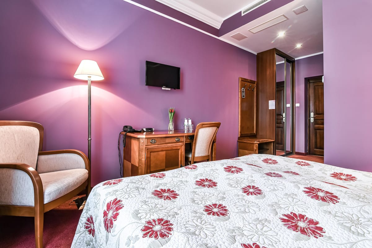 Une chambre d’hôtel équipée d’un lit, d’un bureau, d’une chaise, d’une lampe, d’une télévision et d’une armoire.