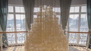 A room with a large chandelier, multiple windows with curtains, and a view of a snowy landscape.