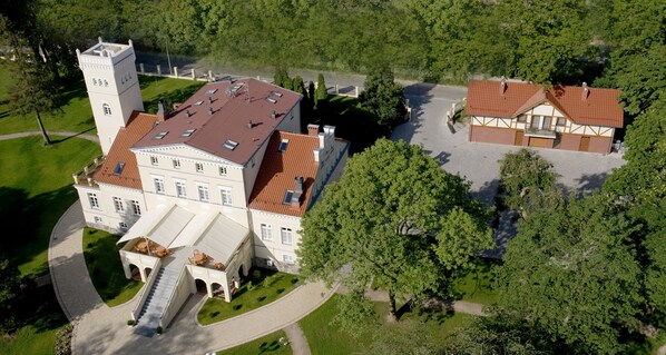A large, historic building with a central tower, multiple wings, and a courtyard.