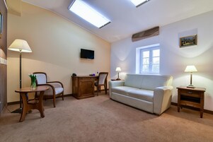 A living room with a sofa, two chairs, a small table, a TV, and a window.