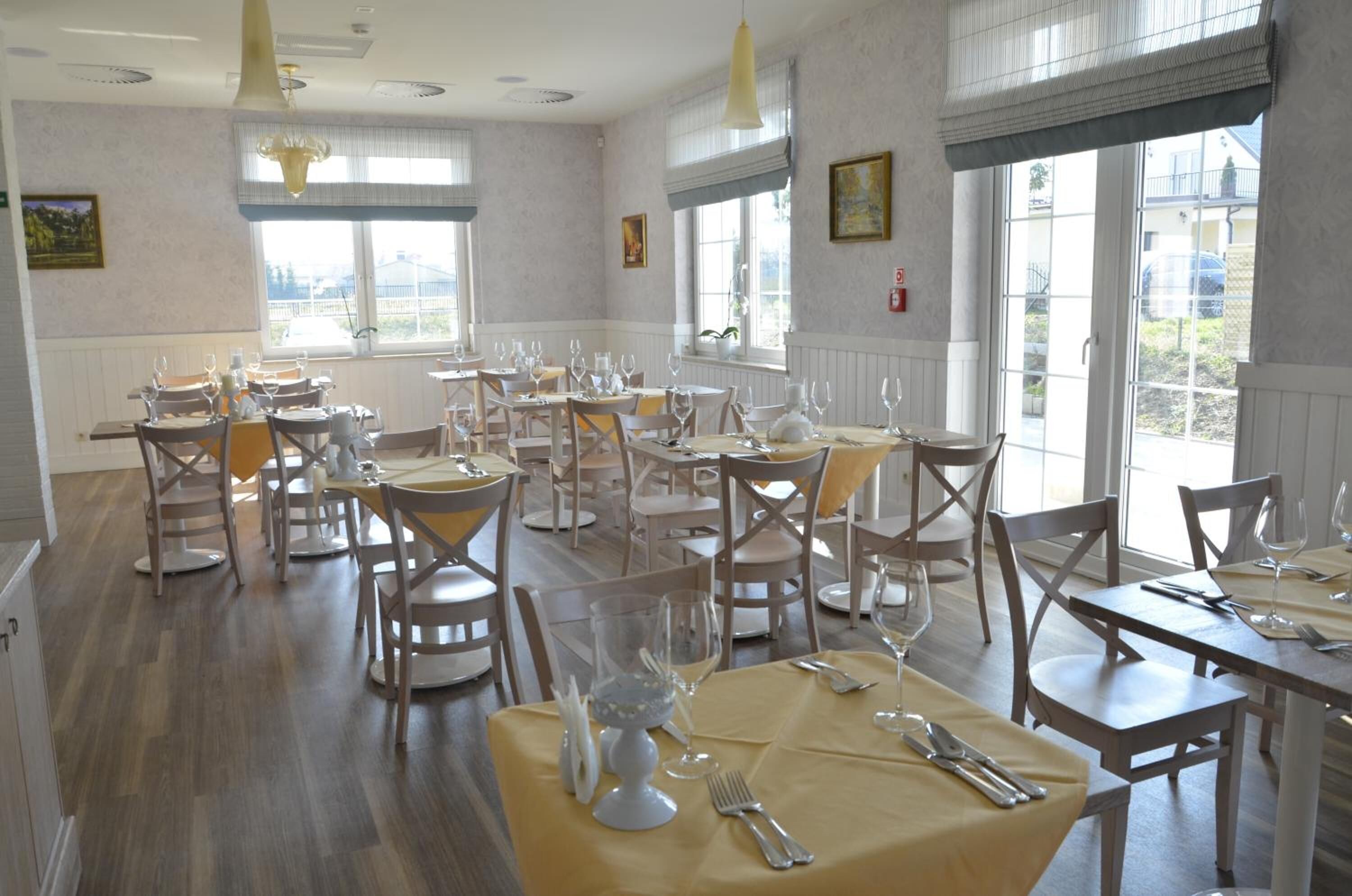 Comedor con varias mesas dispuestas para comensales, con sillas de madera y mantel amarillo.