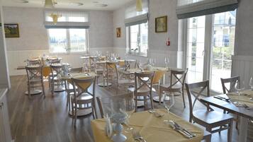 Comedor con varias mesas dispuestas para comensales, con sillas de madera y mantel amarillo.