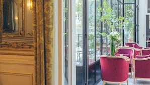 A room with a large window, red chairs, and a potted plant. - Hotel Alfred Sommier (Paris)