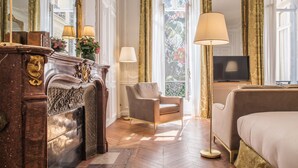 A hotel room with a fireplace, a sofa, a bed, and a television. - Hotel Alfred Sommier (Paris)