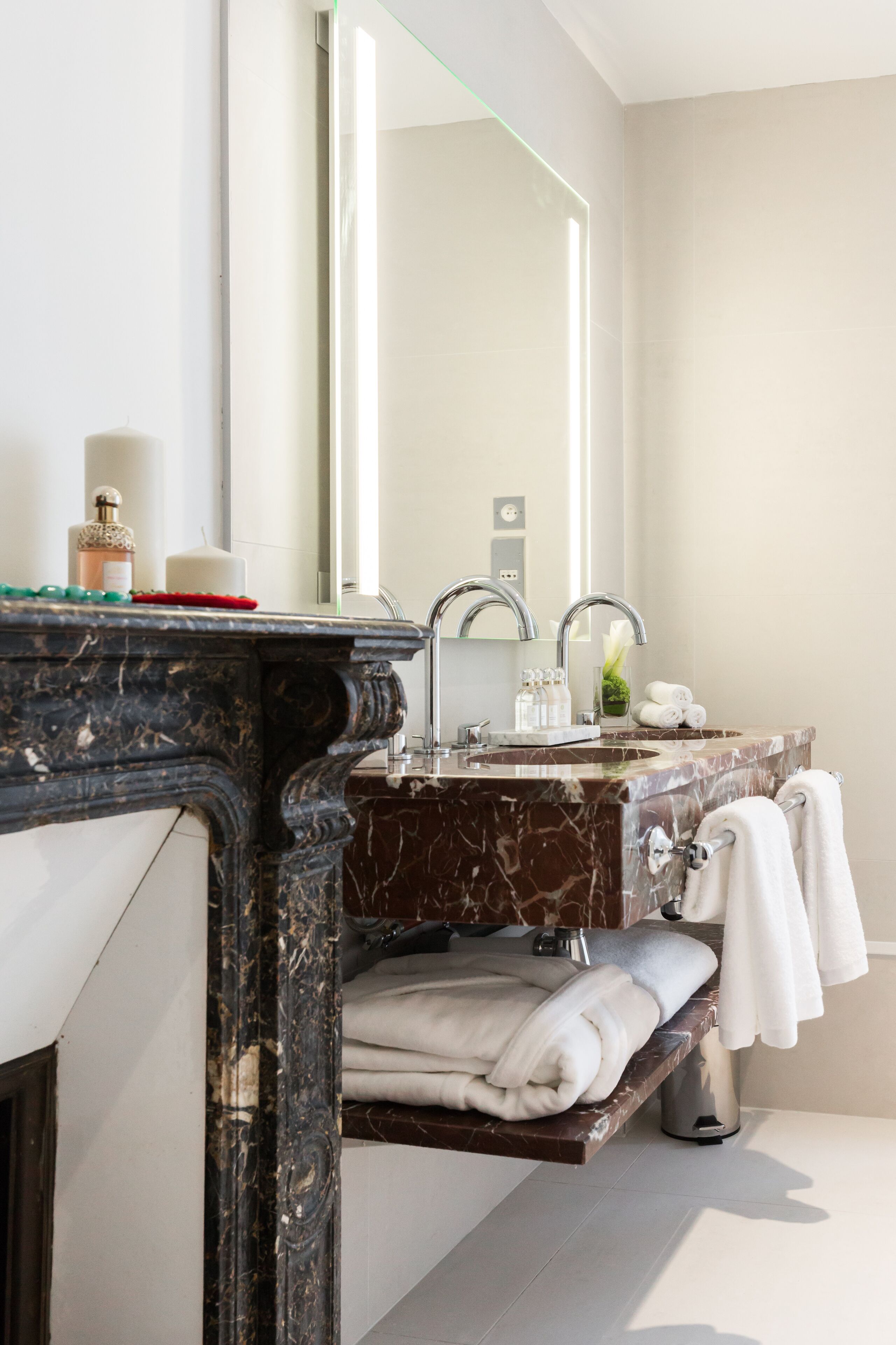 Une salle de bain moderne avec un lavabo en marbre, un grand miroir et un porte-serviettes.
