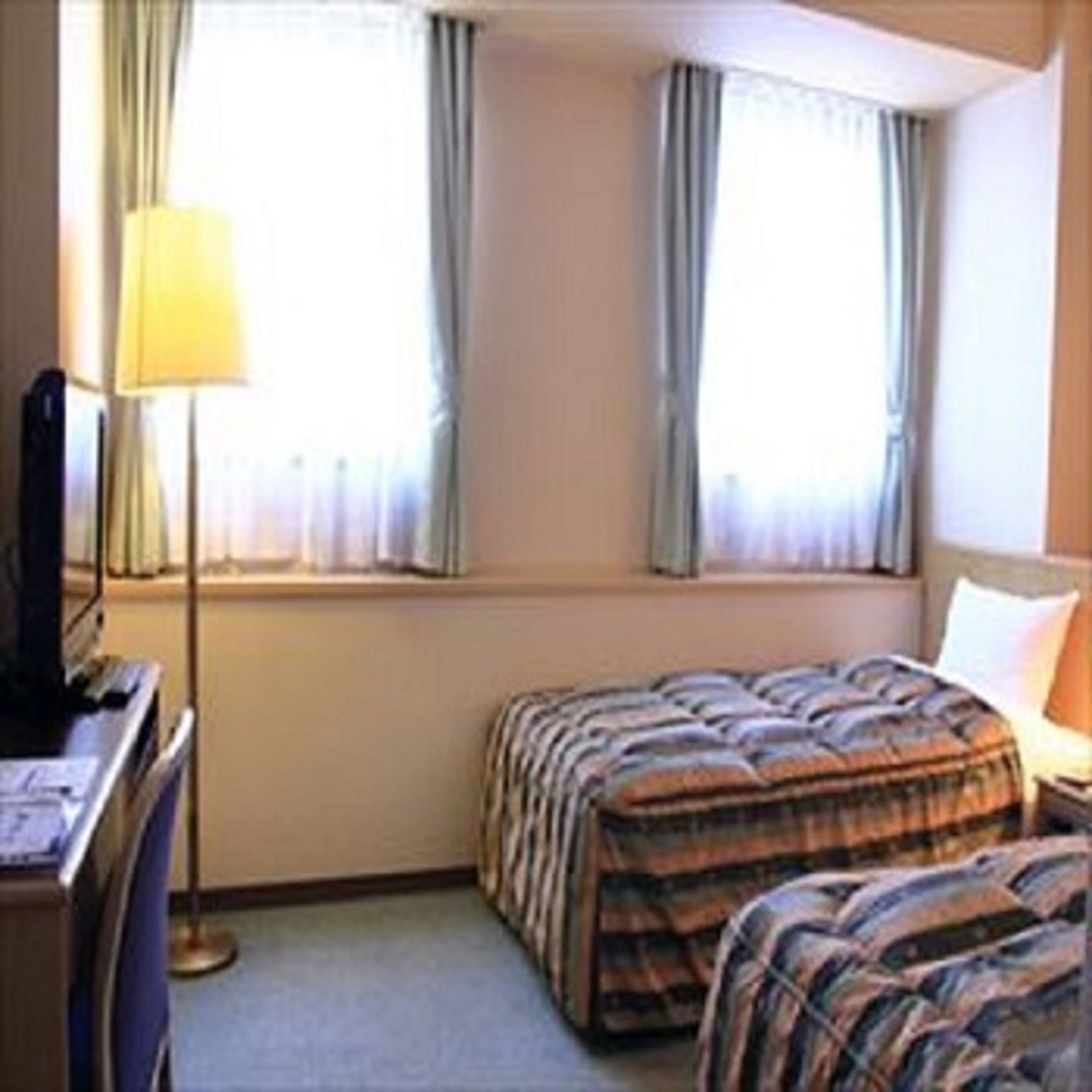A hotel room with a bed, a desk, and a lamp.