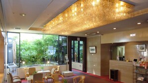 A modern hotel lobby with seating areas, a reception desk, and a view of greenery outside. - Takasaki Urban Hotel (Takasaki)