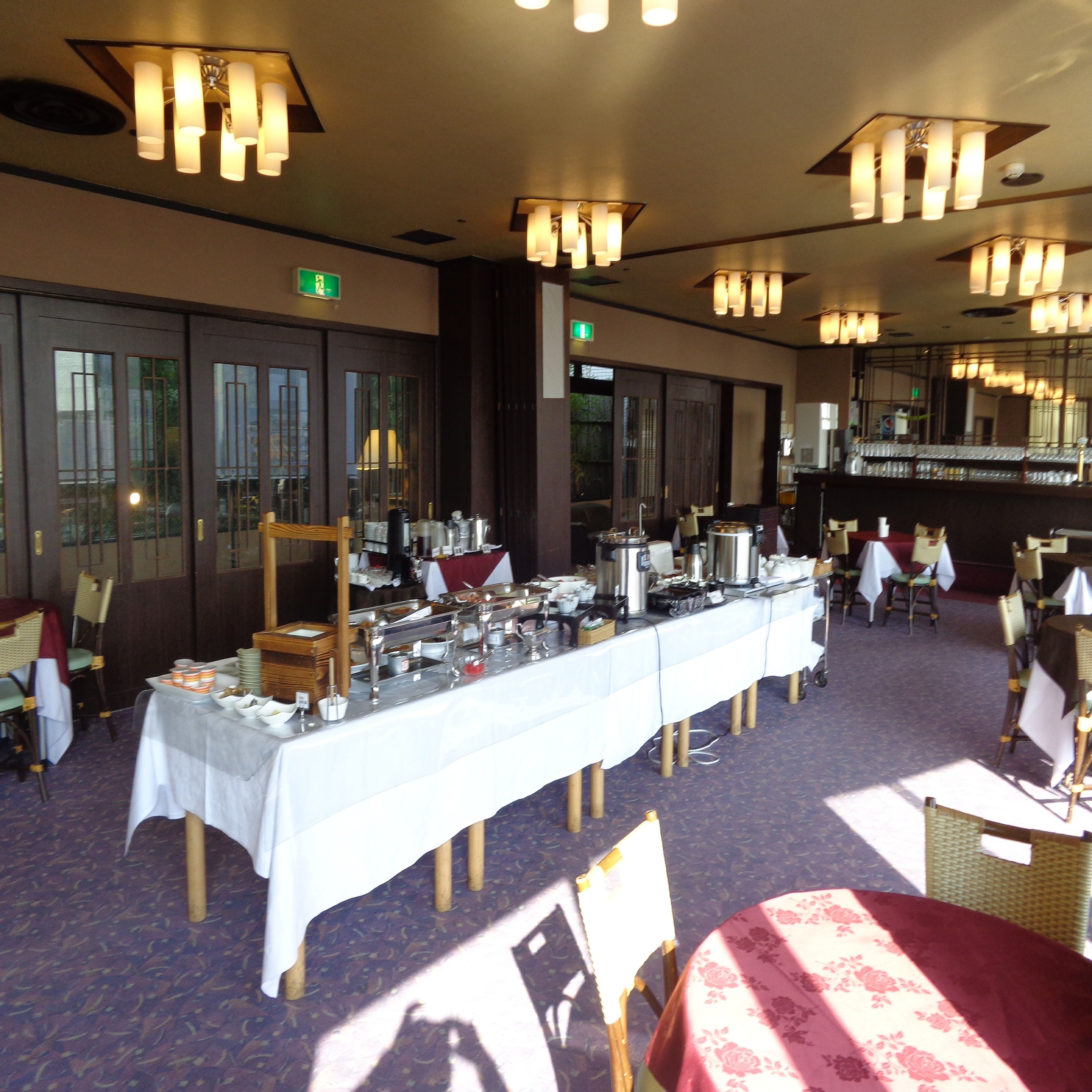 A banquet hall with a long table set for a buffet, surrounded by chairs and tables.