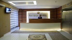 A hotel reception area with a modern design, featuring a reception desk, a television screen, and a reception counter. - Gevher Hotel (Kayseri)