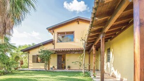 A two-story house with a covered porch, a small garden, and a clear sky. - Lovely home in S. Maria di Ricadi VV with WiFi (S. Maria di Ricadi VV)