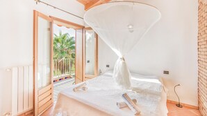 A room with a bed, a large window, and a view of palm trees outside. - Lovely home in S. Maria di Ricadi VV with WiFi (S. Maria di Ricadi VV)