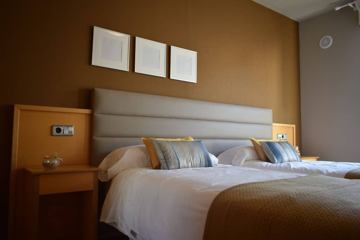 A hotel room with a large bed, two bedside tables, and three framed pictures on the wall.