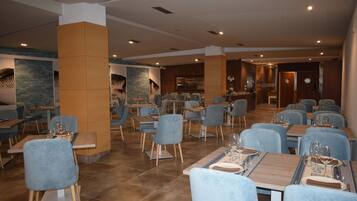 Un restaurante con varias mesas y sillas, piso de baldosas y una decoración interior moderna.