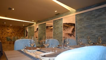 A restaurant with stone walls, blue chairs, and tables set for dining.