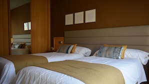Habitación de hotel con dos camas, cabeceros de madera y una paleta de colores neutros.