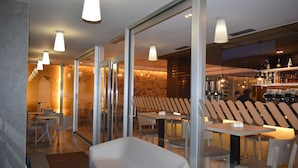 Un restaurante moderno con paredes de vidrio, mobiliario blanco e iluminación colgante.