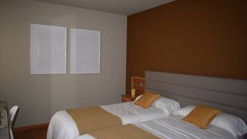 A hotel room with two beds, a nightstand, and a wall-mounted clock.