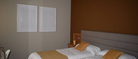 Habitación de hotel con dos camas, una mesita de noche y un reloj en la pared.