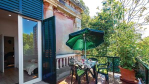 A patio with a table and chairs, an umbrella, and a potted plant.