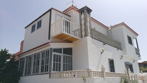 A two-story building with a balcony, large windows, and a white facade.