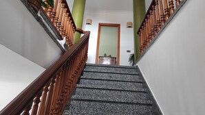 A staircase with wooden balusters and granite steps leading to a room with a green accent wall and a wooden door.