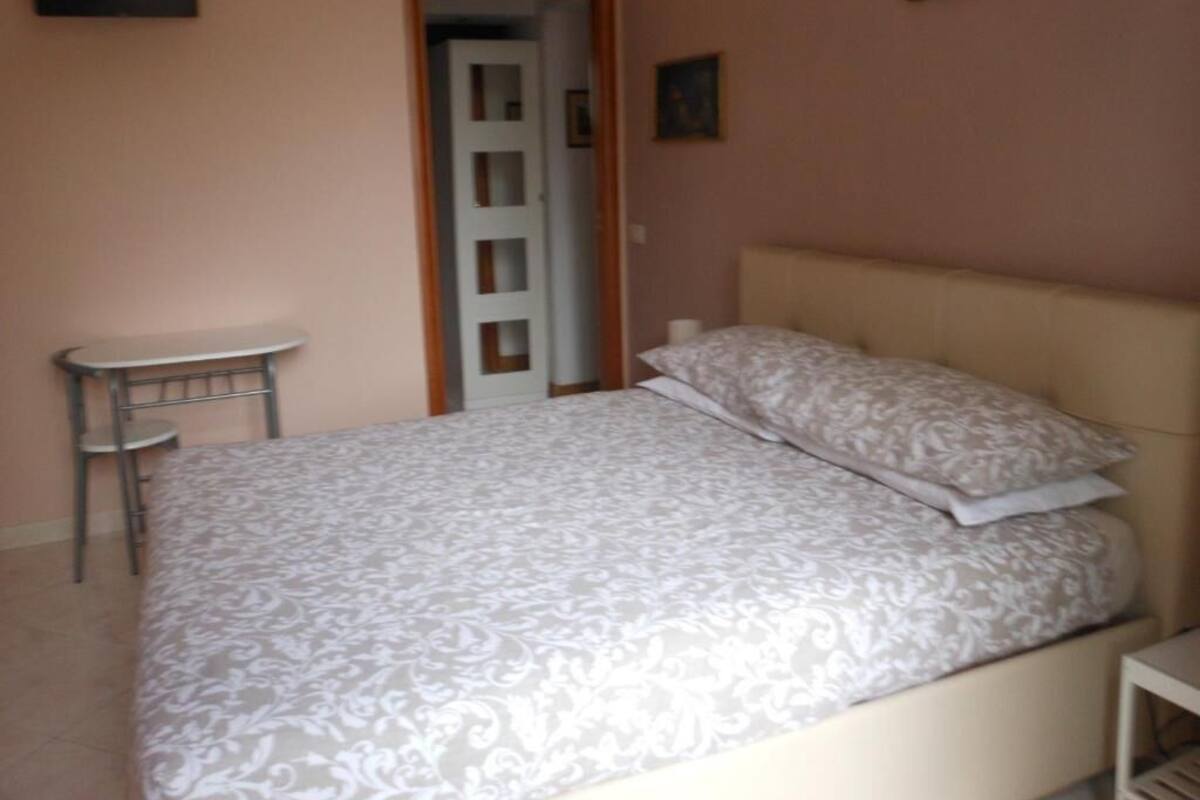 A bedroom with a bed, a small round table, and a door leading to another room.