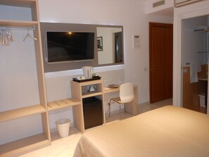 A hotel room with a bed, a desk with a chair, a mirror, and a wardrobe. - Domus Chiara al Colosseo (Rome)