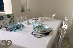 Una mesa de comedor dispuesta con platos a rayas azules y blancas, vasos y una tetera.