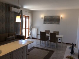 Un comedor con una mesa, sillas, un sofá, un televisor y un cuadro en la pared.