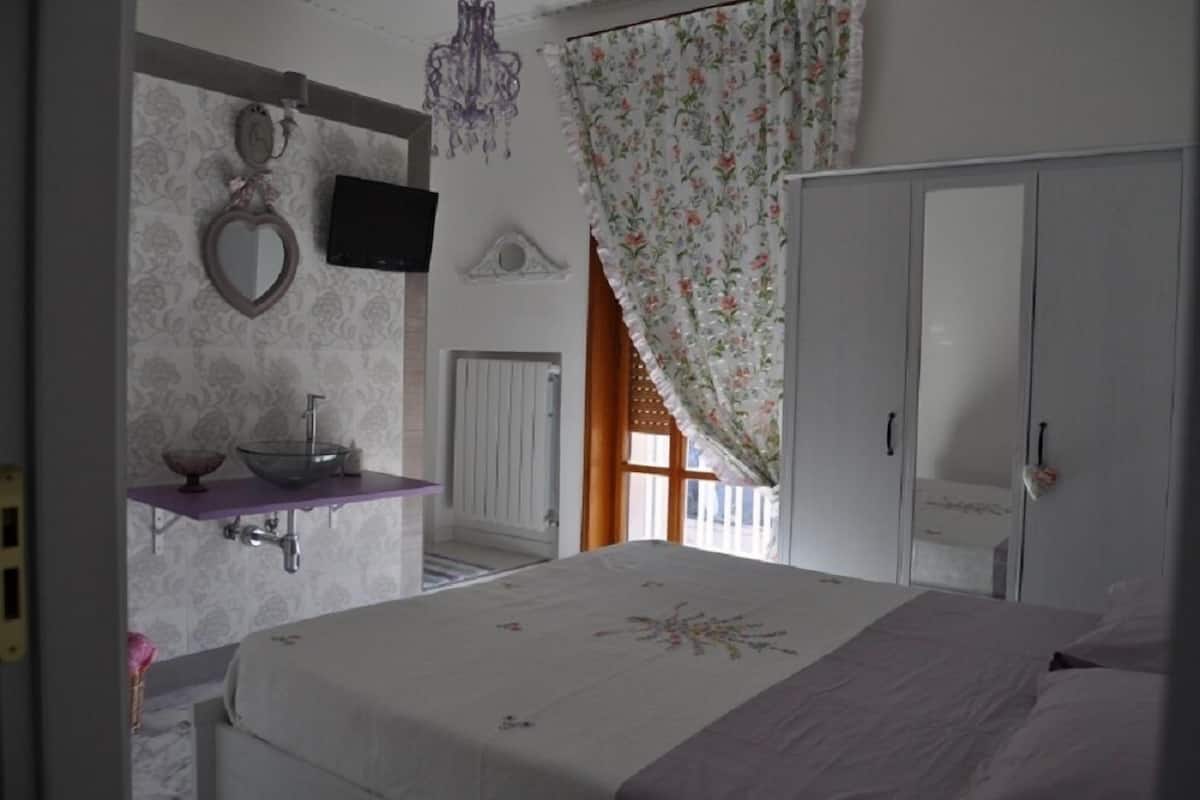 Une chambre à coucher comprenant un lit, une coiffeuse avec un miroir et un récipient, une télévision, un lustre et une armoire.