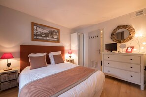 Una camera da letto ordinata con un letto, due lampade da comodino, una cassettiera, una televisione e un quadro incorniciato.