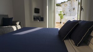 Un dormitorio con una cama, un sofá, una planta en maceta y vistas a un acantilado.