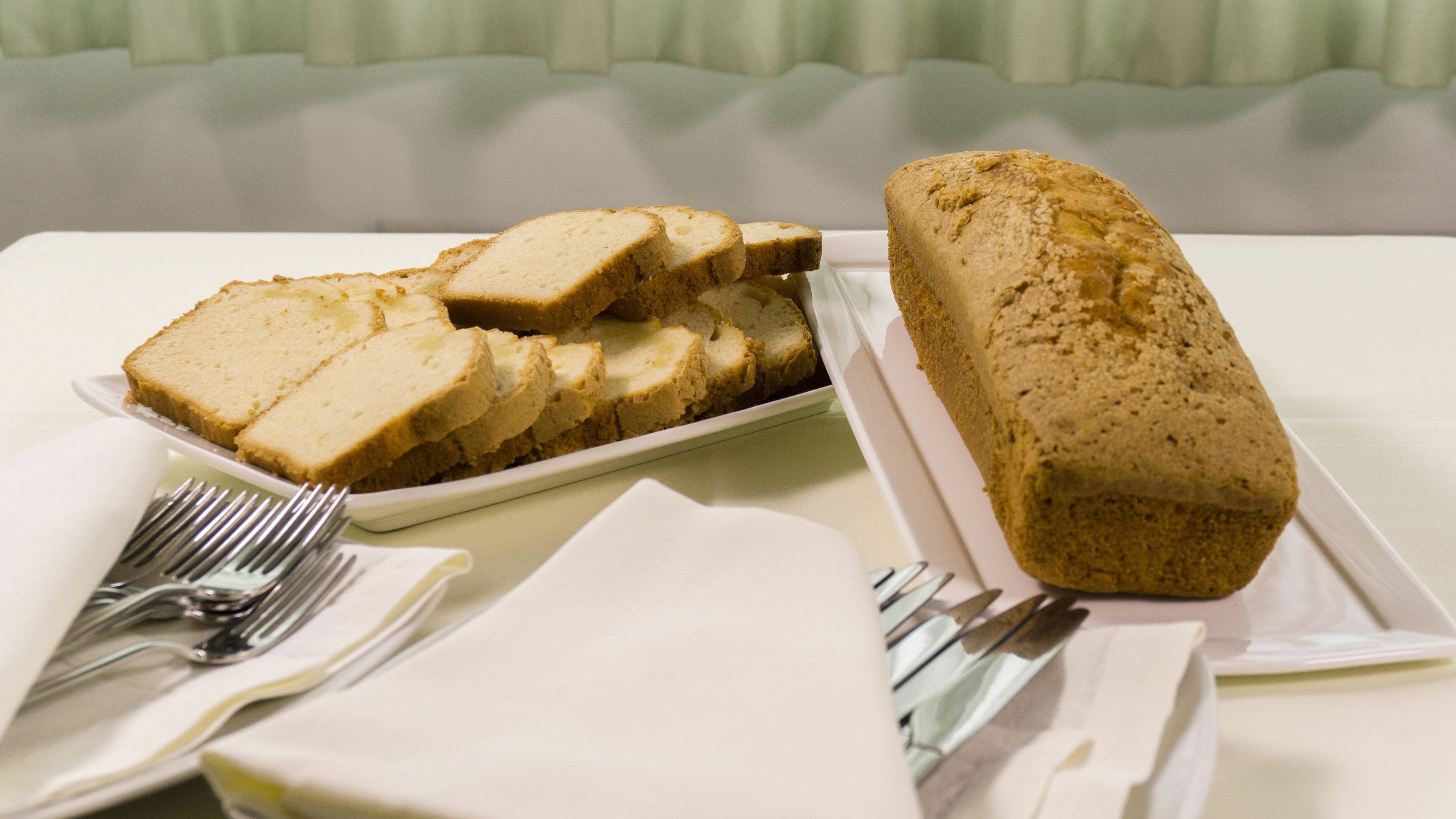 A slice of bread on a white plate with a fork beside it.