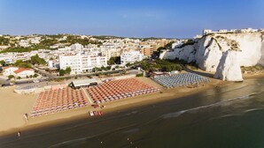 Un pueblo costero con una zona de playa que muestra hileras de sombrillas y tumbonas.