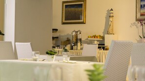 A dining area with tables set for guests, a coffee machine, and a decorative lighthouse on the wall. - Hotel Scialara (Vieste)