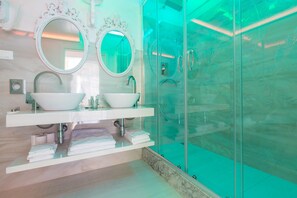 A modern bathroom with two sinks, a glass shower enclosure, and decorative mirrors.