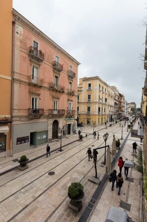 A pedestrian street lined with multi-story buildings, featuring a mix of architectural styles and balconies.
