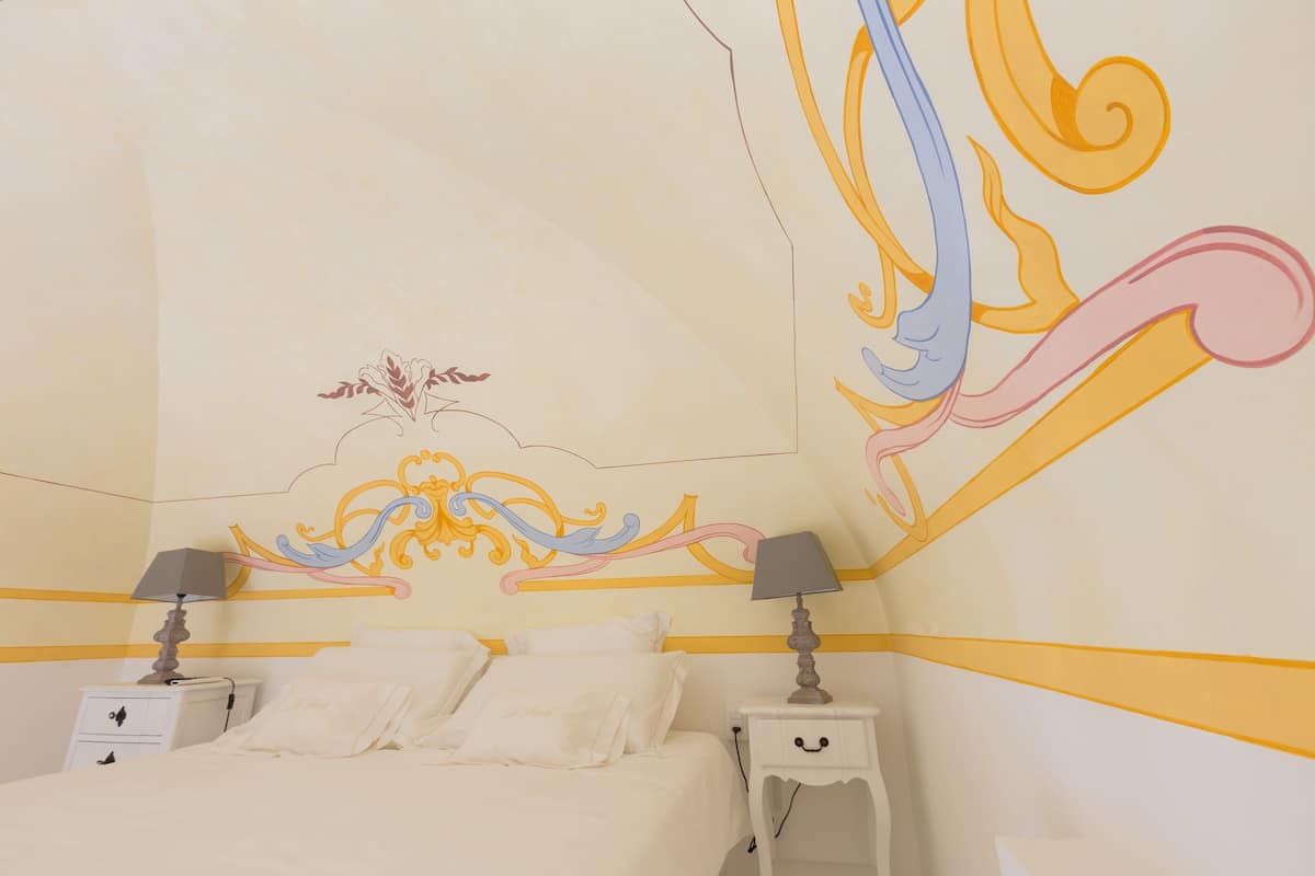 Ein Schlafzimmer mit einem Bett, zwei Nachttischen und einer Wand mit einem dekorativen Wandgemälde.