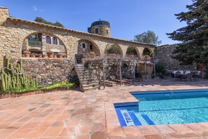 A stone building with a pool, arched windows, and outdoor seating. - Mas Tomas (Vall-Llobrega)