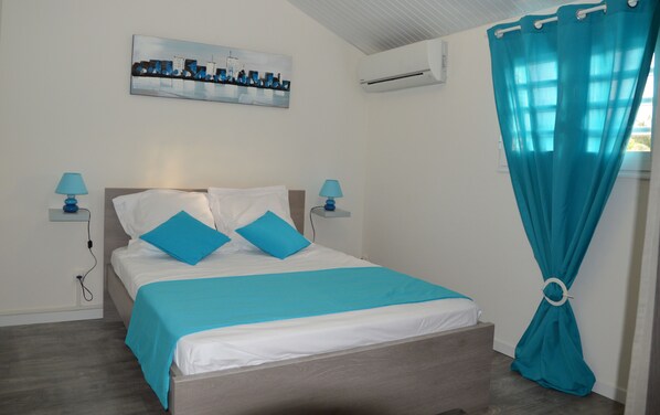 Une chambre à coucher avec un lit, deux lampes de chevet, un climatiseur fixé au mur, un tableau et un rideau.