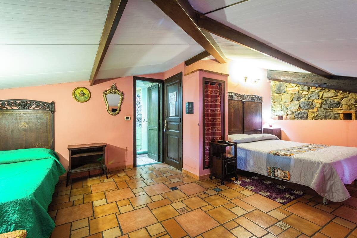 A bedroom with a green bed, a wooden headboard, a stone wall, and a tiled floor.