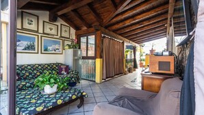 A cozy living room with a sofa, a chair, a table with a patterned tablecloth, and a television. - B&B Villa Felice (Giardini Naxos)