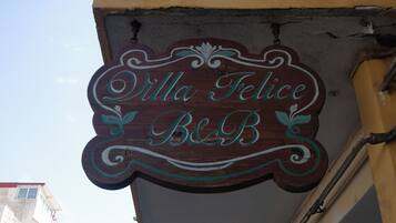 Een houten bord met de naam 'Villa Felice B&B' in sierlijke letters.